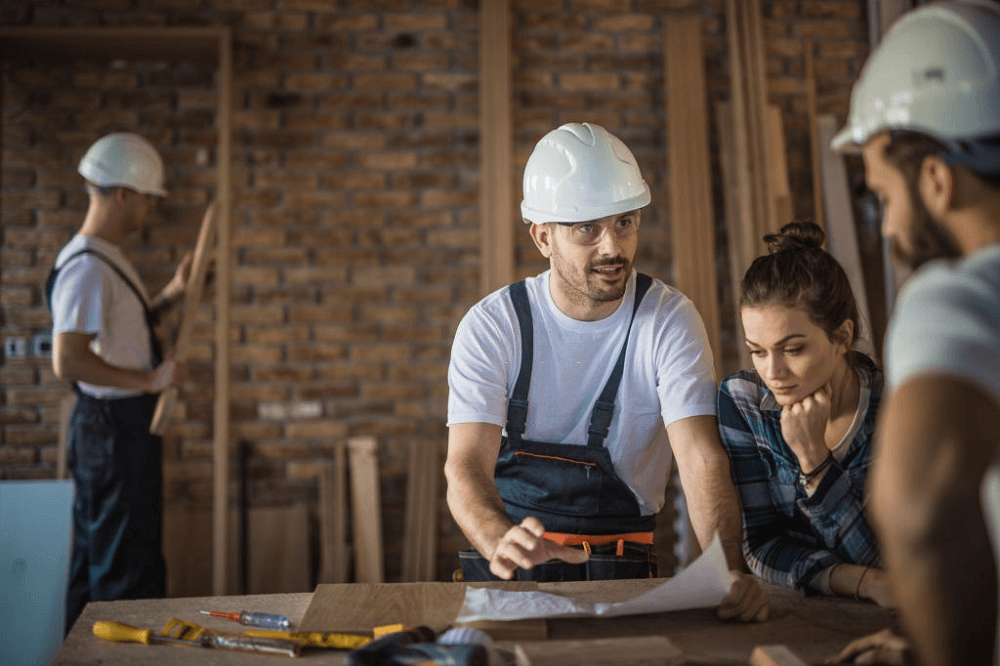 builders and a buyer reviewing home blueprint