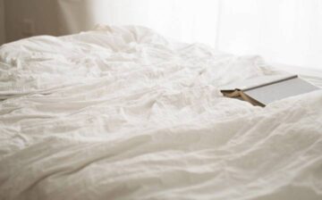 bed with sheets and book on top