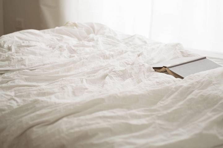 bed with sheets and book on top