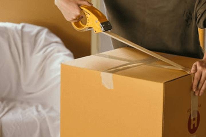 woman closing moving box with tape
