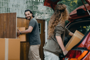 young couple loading moving boxes into a car