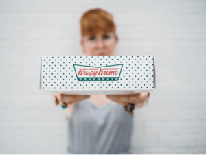 woman holding out Krispy Kreme box