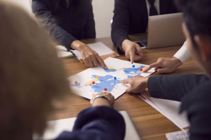 group pointing at a map with points marked