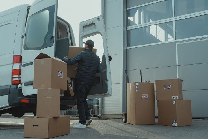 man loading moving boxes into a van