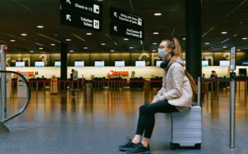 woman sitting on suitcase in airport