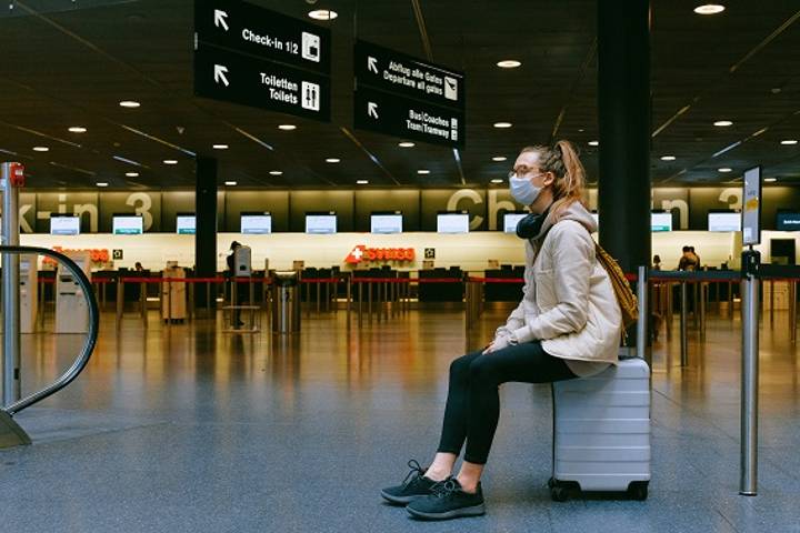 woman sitting on suitcase in airport