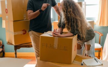 a man and a women standing by moving boxes