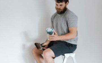 man seats on a chair with paint in his hands