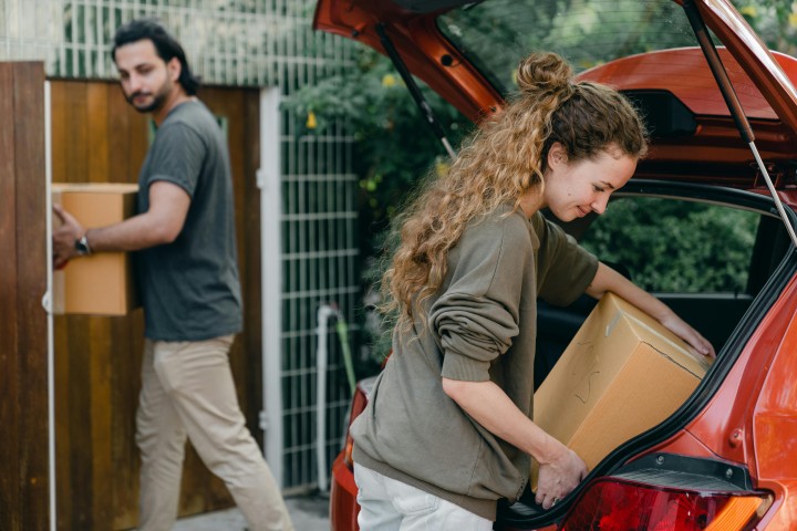 man and a woman loading moving boxes to a car