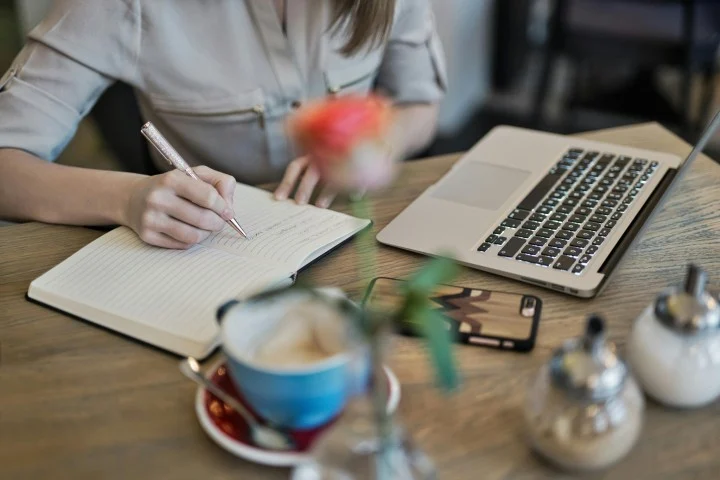 hands writing in diary and computer