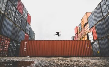 man jumping on top of ocean shipping container