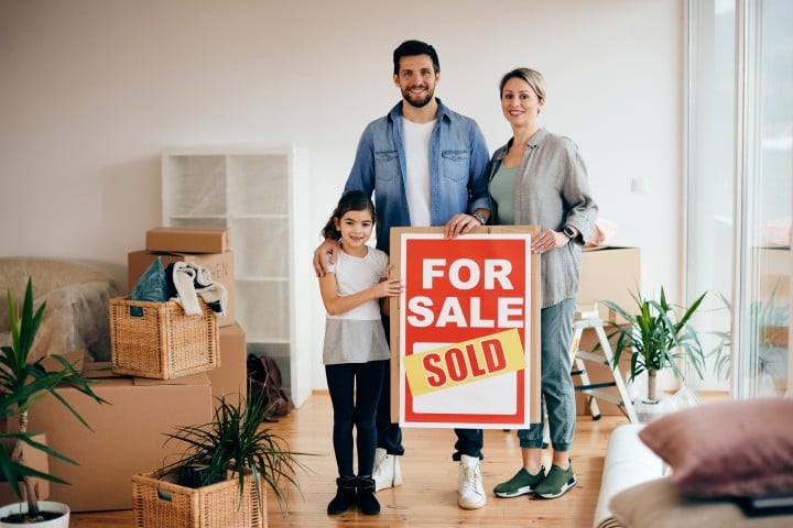 family with house sold sign