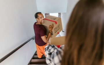 man going down ladder with moving box