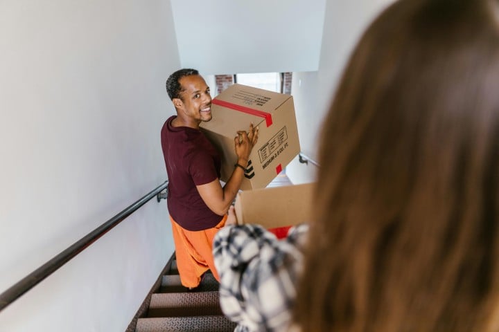 man going down ladder with moving box