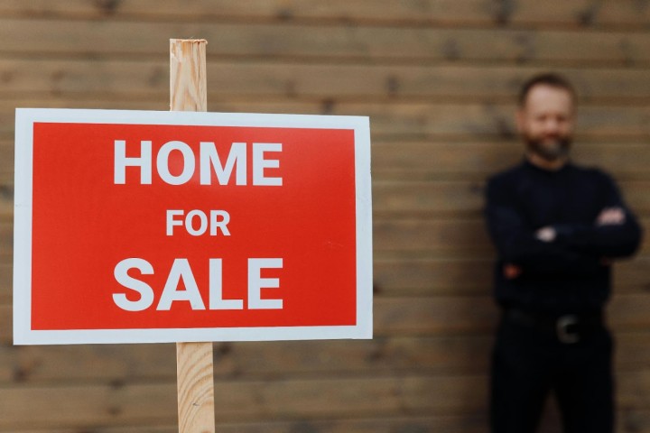 man holding house sign home for sale