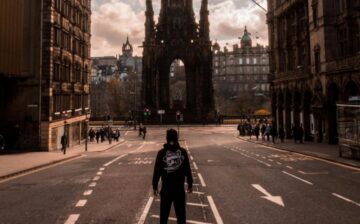 man in the middle of the street in edinburgh with castle in front