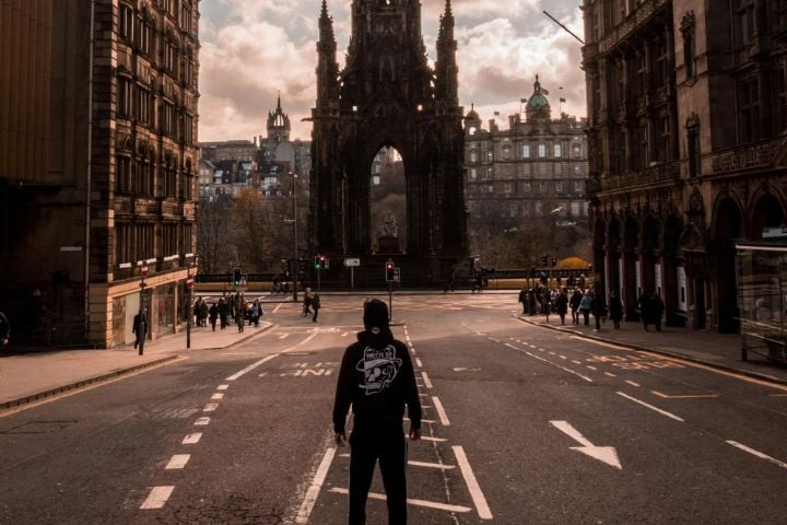 man in the middle of the street in edinburgh with castle in front