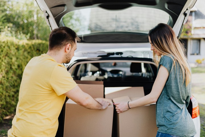 couple unloading moving boxes from the car