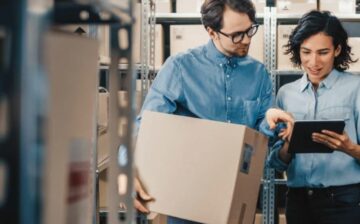 couple with moving box in hand and watching tablet