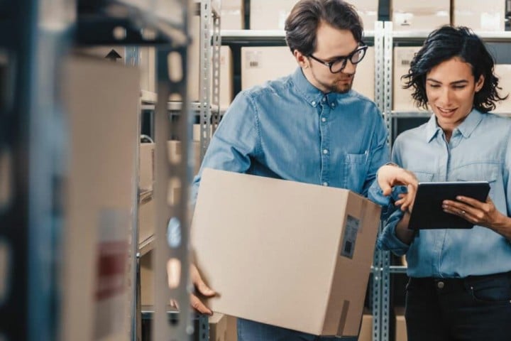 couple with moving box in hand and watching tablet