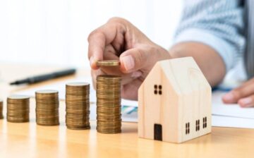 man making stacks of coins with house in small