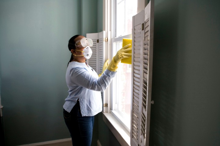 woman cleaning window of house for sale