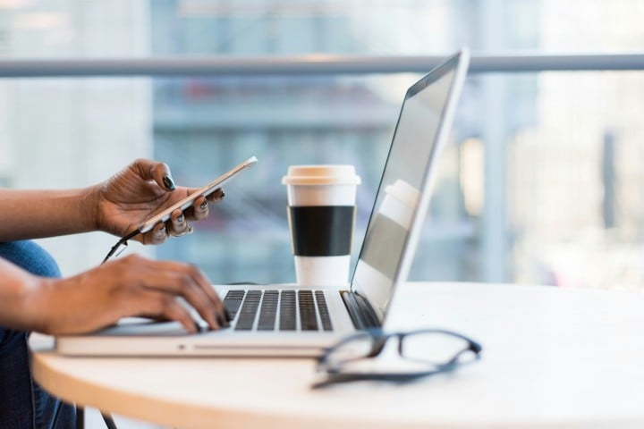woman with cell phone and computer having coffee