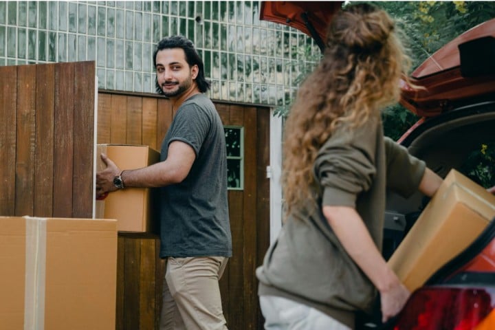 couple unloading moving boxes from car