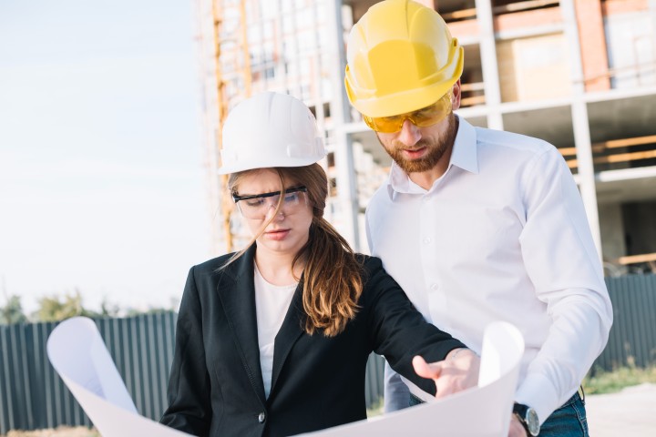 man and woman working in construction looking at blueprint