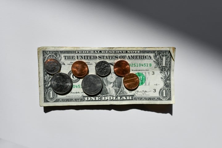 one dollar bill with coins on top