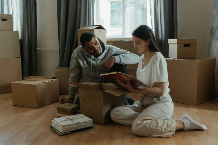 couple looking at album between moving boxes