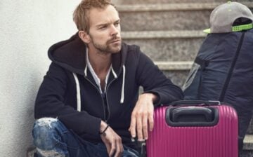 a person seating on a staircase with a suitcase