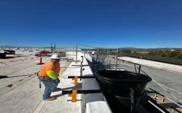 Workers installing heavy duty debris chutes for demolition using electric winch and scaffold anchors at a construction site