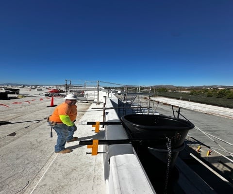 Workers installing heavy duty debris chutes for demolition using electric winch and scaffold anchors at a construction site
